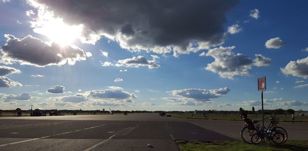 Cars parked on road against cloudy sky