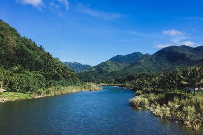 Scenic view of river and mountains against blue sky