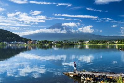 Man standing on pier while fishing in lake