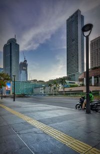 Road by buildings against sky in city