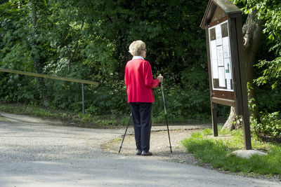 Rear view of senior woman with walking canes looking at road map