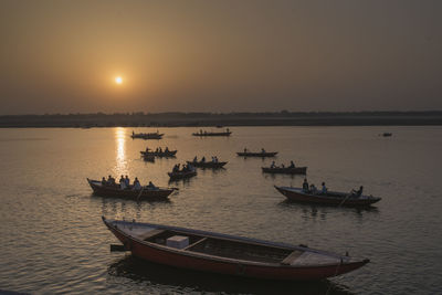 Boats in sea at sunset