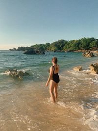 Full length of woman standing in sea against sky