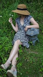 Midsection of woman sitting on grass in field