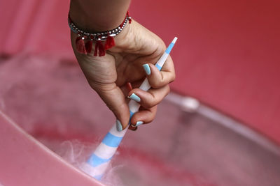 Cropped hand of woman holding cone in container