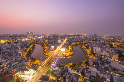 High angle view of illuminated city against sky at dusk