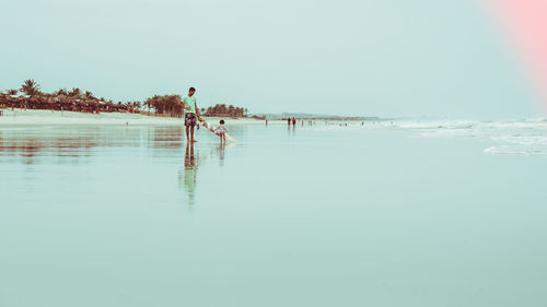 People in sea against clear sky