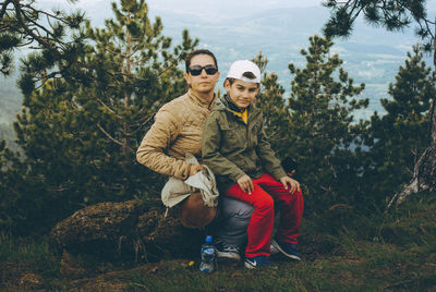 Portrait of father with daughter standing against trees in forest