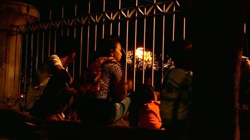 People sitting in illuminated fire at night