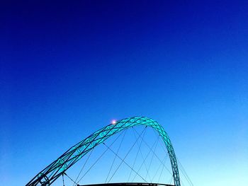 Low angle view of ferris wheel against clear blue sky