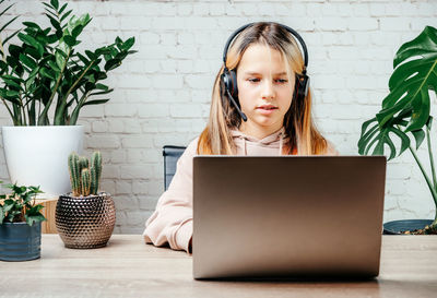 Student girl in headphones watching online video zoom class webinar in virtural classroom on her