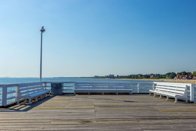 Pier on sea against clear blue sky