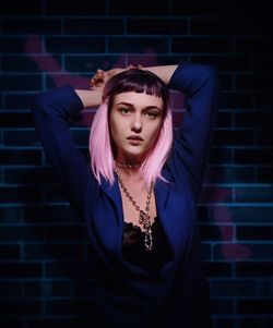 Portrait of young woman standing against wall