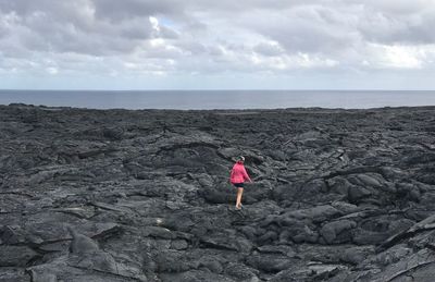 Woman walking on rocks against sky