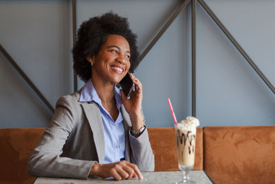 Smiling businesswoman talking over smart phone in cafe
