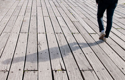 Low section of man walking on wooden footpath