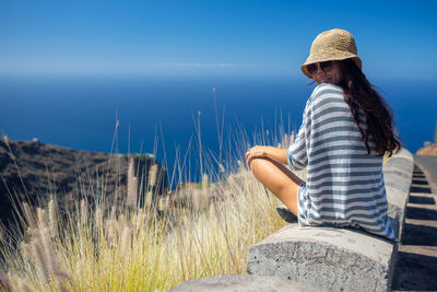 Rear view portrait of woman sitting outdoors