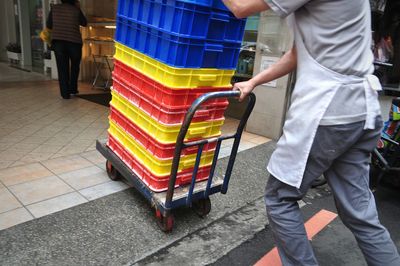 Midsection of man pushing cart with colorful crates