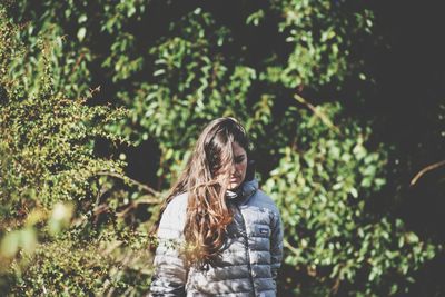 Woman standing by tree in forest