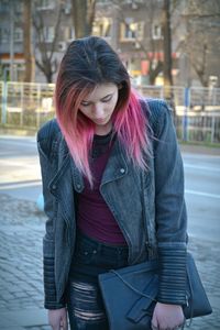 Young woman standing on sidewalk in city