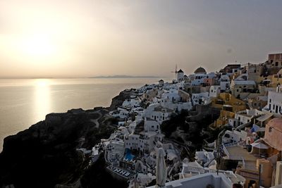 Buildings by sea against sky during sunset
