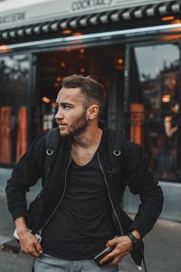 Thoughtful young man standing against building in city