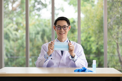 Portrait of a smiling young man sitting on table