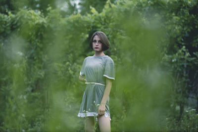 Portrait of woman standing against trees