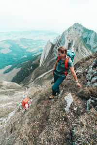 Two active female climbers ascending steep grass mountain in ch