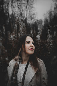 Young woman standing against trees