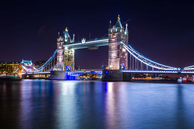 Illuminated suspension bridge over river at night