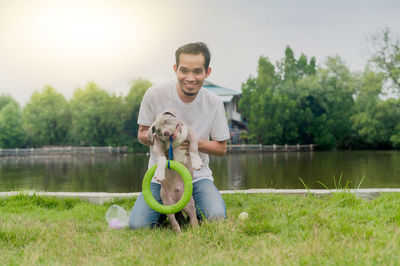 Full length of smiling man holding lake in grass