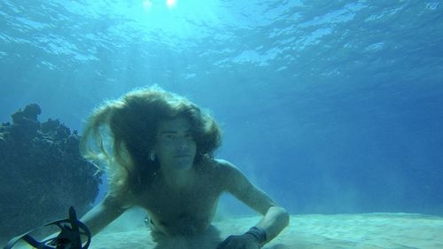 Shirtless man on ocean floor