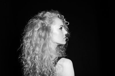 Close-up of woman with curly hair against black background