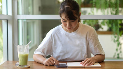 Young woman sitting with drink on table