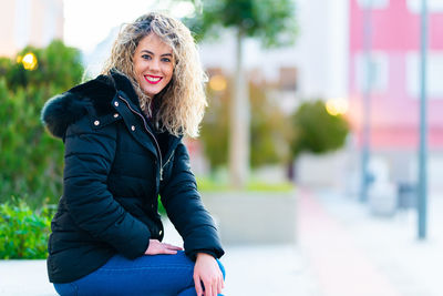 Portrait of smiling young woman with blond hair sitting outdoors