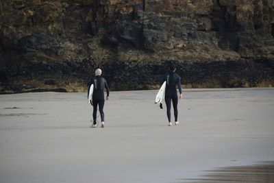 Rear view of men walking on beach