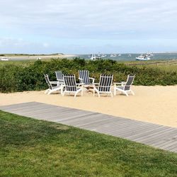 Empty chairs on beach against sky