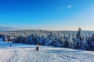 Woman skiing on field against blue sky during winter