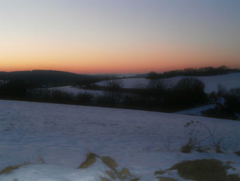 Scenic view of frozen landscape against sky during sunset