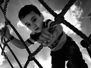 Low angle view of boy playing on jungle gym against sky