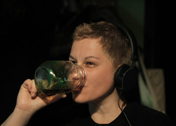 Close-up of woman drinking black coffee while listening music
