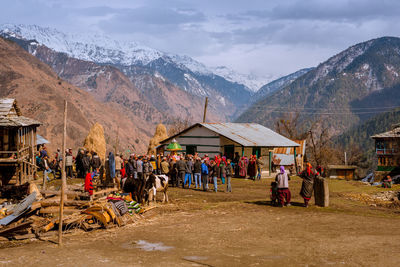Group of people by buildings against mountain range