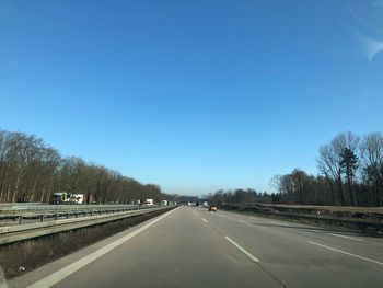 Road in city against clear blue sky