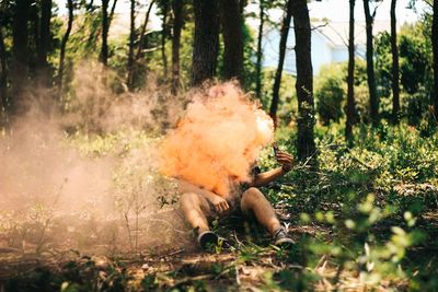Man with distress flare emitting smoke in forest