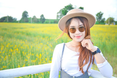 Young woman wearing sunglasses while standing on field