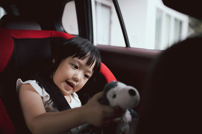 Cute girl playing with toy while sitting in car