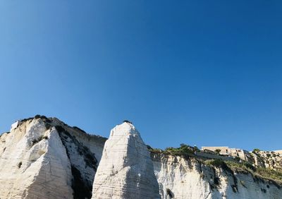 Low angle view of rock formations against clear blue sky