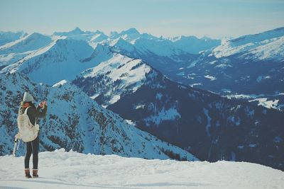 Man standing on snowcapped mountain against sky