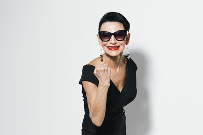 Portrait of young woman wearing sunglasses against white background